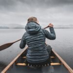 a woman paddling a canoe on a lake