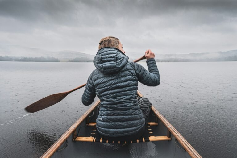a woman paddling a canoe on a lake