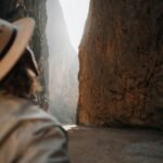 a person wearing a hat standing in front of a mountain